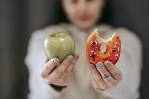 woman showing apple and bitten doughnut stockpack pexels 300x200 - How to Implement a Raw Food Diet