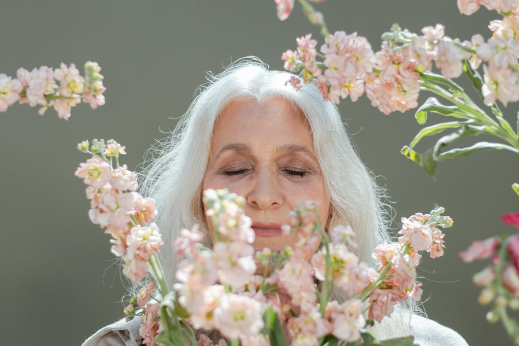 woman with white hair surrounded by white and pink flowers stockpack pexels 1024x683 - Essential Vitamins for Fighting Grey Hair!