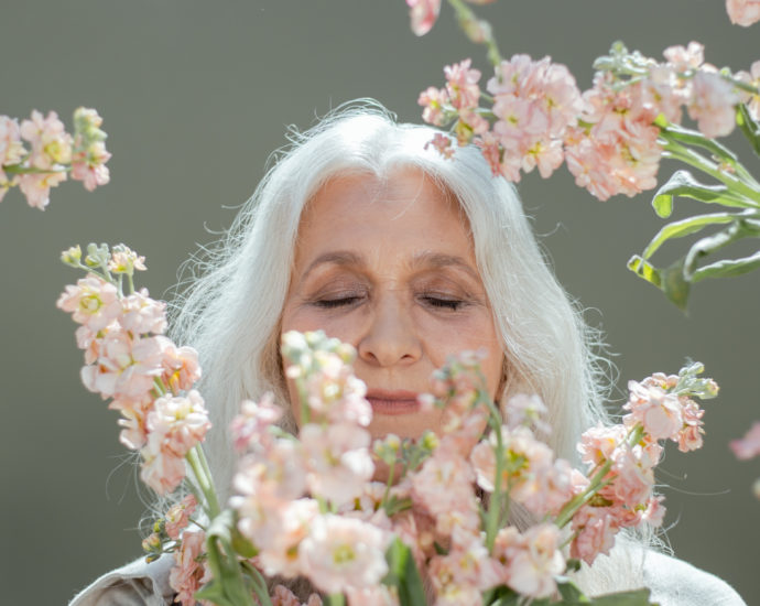 Woman with white hair surrounded by white and pink flowers